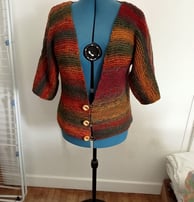Vest original tricoté dans un fil multicolore se ferme par 3 boutons et les manches trois quart