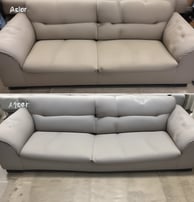 A unique green sofa composed of multiple overlapping cushions, arranged in a modern and artistic fashion. The sofa rests on a metal frame and is placed against a backdrop of white curtains, with a neutral-colored carpet underneath.