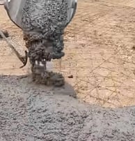 Concrete being poured into a driveway that has rebar positioned already which provide stability.