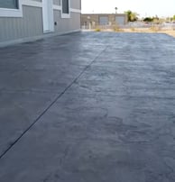 a stamped concrete patio area in the rear of a house colored in grey cement