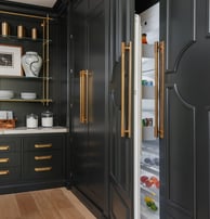 a kitchen with black cabinets and gold accents