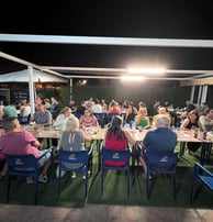 a group of people sitting at a table with food