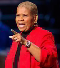 a woman in a red jacket and black top speaking to a crowd