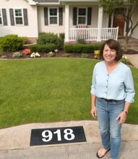 Lady standing next to her freshly painted Address number"918", very happily.