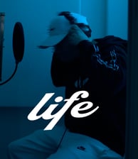 Albumcover mit der Titel "life" Person mit Kopfhörern im Hintergrund, weiß auf blau