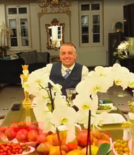 a man sitting at a table with a large vase filled with flowers