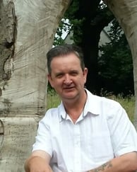 Bruce Clifton sitting in front of a memorial to the oldest trees in Cumbria, UK