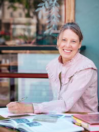a woman sitting at a table with a pen and paper