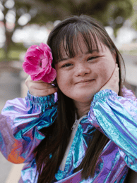 a beautiful young women with downs with a pink flower in her hair