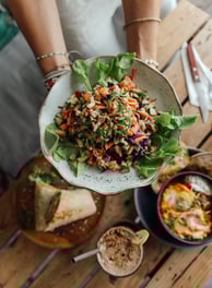 a person holding a plate with a salad on it