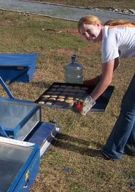 Jenny is taking cookies out of the solar oven