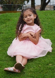 Niña sentada en el pasto sonriendo