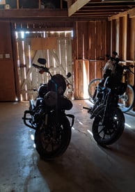 two motorcycles parked in a garage with a bike
