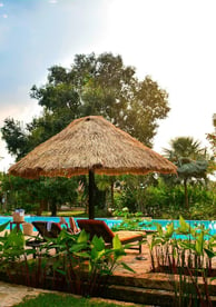 a pool with a thatched umbrella and chairs