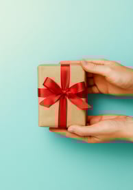 Mãos entregando um presente com laço vermelho, simbolizando oferta gratuita do eBook cristão