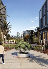 A family walking along One Ninety’s pedestrian promenade surrounded by palm trees, fountains