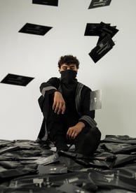 a man in a black shirt and black pants sitting on a pile of black and
