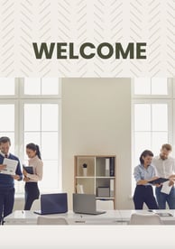 a group of people standing around a desk with a welcome sign