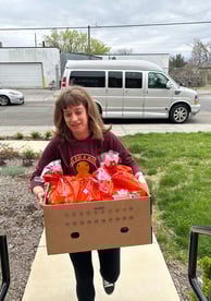 a woman holding a box of food in front of a van