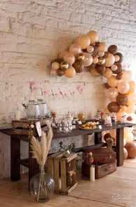 Un mur en brique décoré de ballons et guirlande.Une table avec des bocal à bonbons