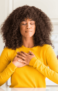 a lovely young black woman expressing gratitude with her hands on her heart