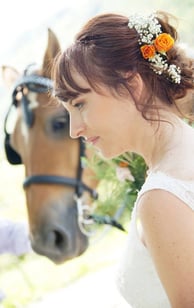 Portrait de mariée avec des fleurs dans les cheveux devant un cheval