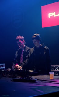 two men standing in front of a dj booth