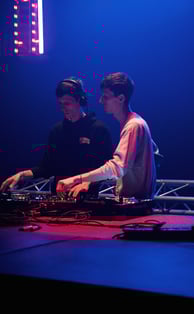 two men standing in front of a stage with a dj and a dj