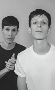 two men standing next to each other in front of a wall