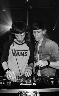 two men standing in front of a dj booth