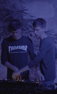 two men standing in front of a wall with a dj booth