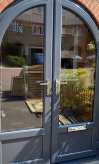 anthracite grey front door with unusual arched shape and reflective glass
