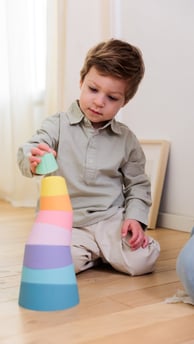 The boy building a tower from colorful stacking rings.
