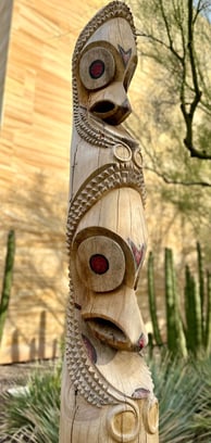 a wooden vanuatuan slit drum with faces carved into it