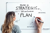 a woman is writing a strategy on a white board