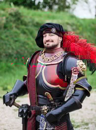 Chevalier en armure noire et rouge portant par dessus une étole en brocard