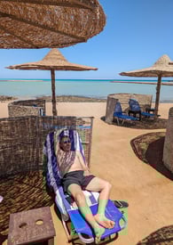 a man laying on a beach chair with a hat on