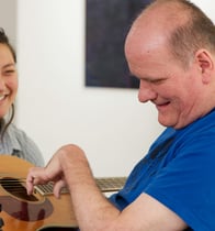 A disabled adult male learning to play the guitar