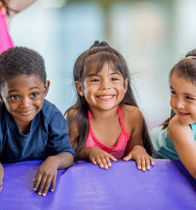 three young children in colorful gym attire are smiling and posing for a picture