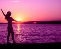 person practicing mindfulness for pain on a beach, using yoga or tai-chi. Purple sunset