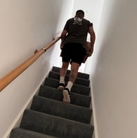a man from deanos removals walking up a flight of stairs with a box