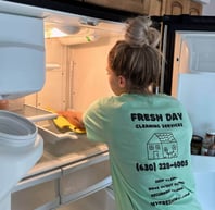 a cleaner in a uniform shirt is clean the refrigerator