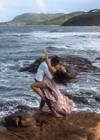 a man and woman kissing on a rock at the beach in Saint Lucia