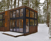 Modern prefab modular tiny home in snowy forest by builders