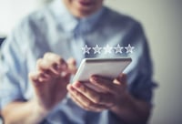 Person using a smartphone to give a five-star online review.
