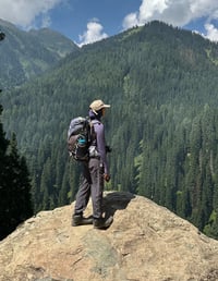 a women with a hiking backpack and hiking boots on a mountain in Kashmir during a hike