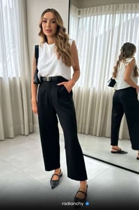 a woman in a white top and black pants