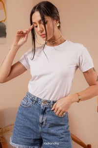 a woman in a white shirt and jeans shorts