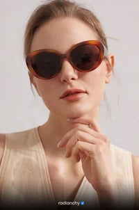 a woman wearing sunglasses and a tan top
