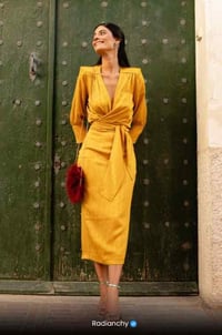 a woman in a yellow dress standing in front of a green door